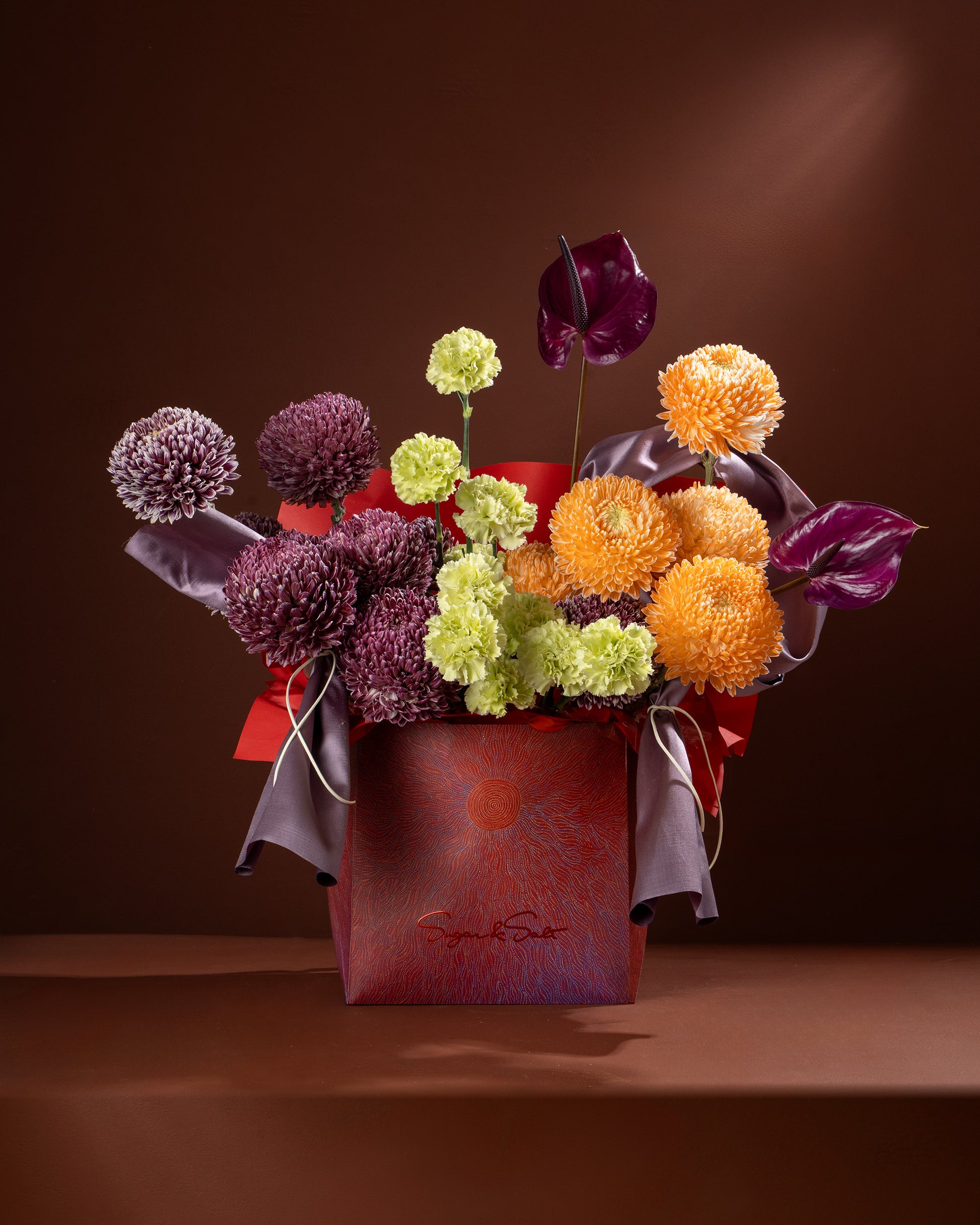 Colorful flower arrangement in a red box on a brown background