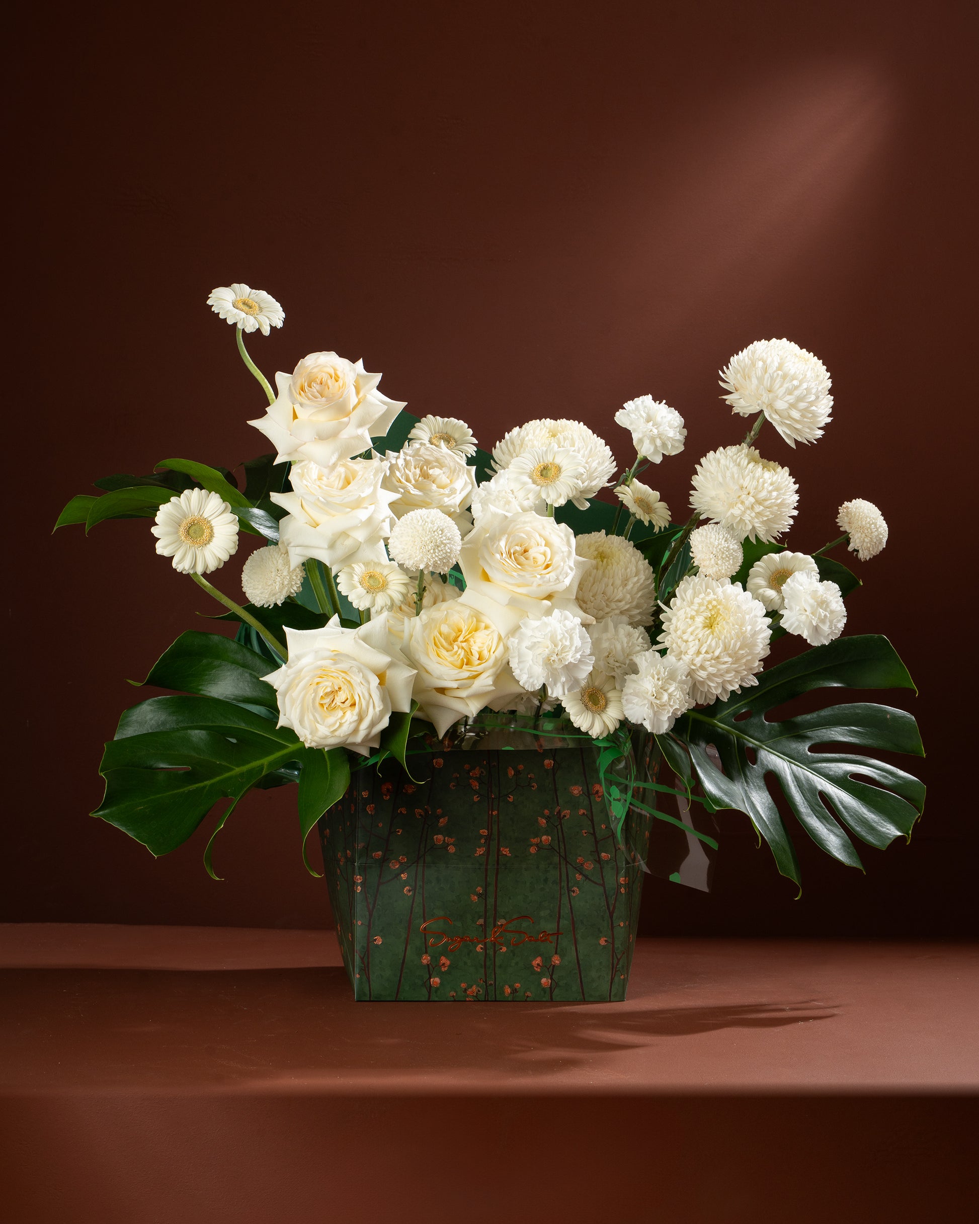Bouquet of white flowers in a green basket on a brown background