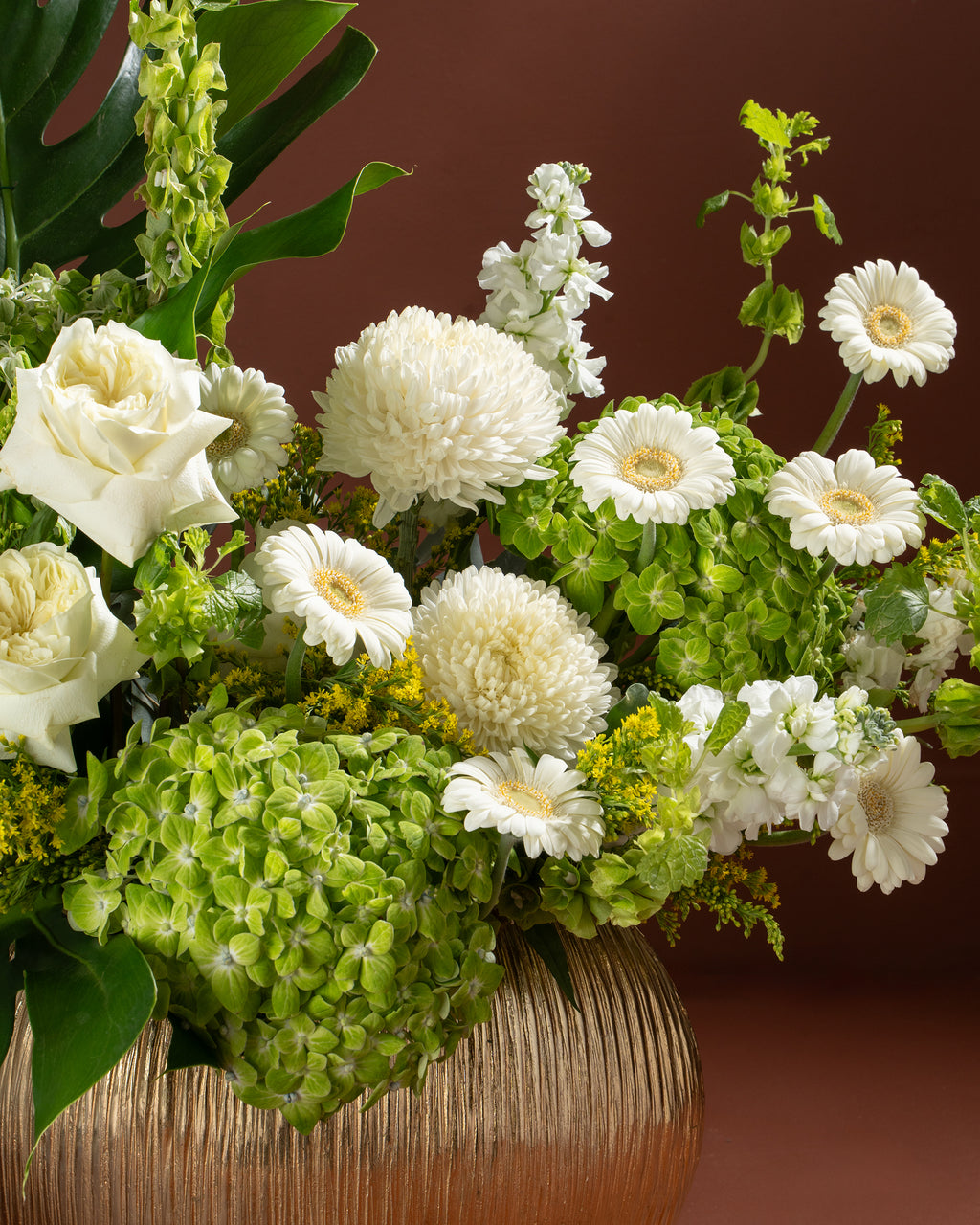 Floral arrangement with white and green flowers in a woven basket on a brown background