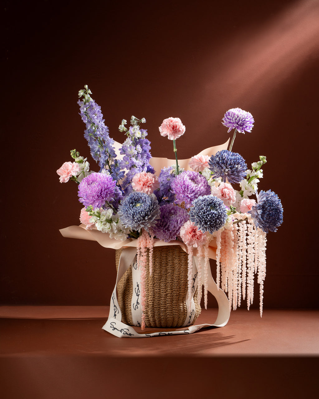 Bouquet of flowers in a woven basket on a brown background