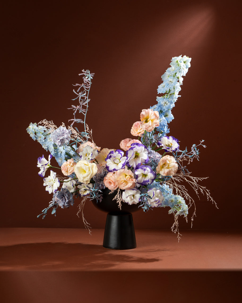 Floral arrangement in a black vase on a brown background
