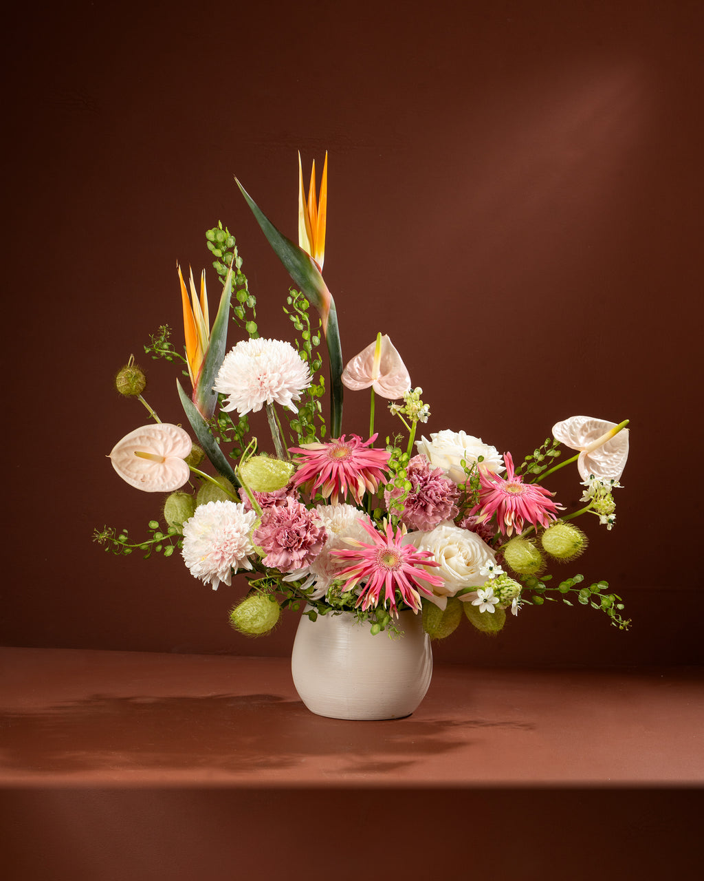 Floral arrangement in a white vase on a brown background