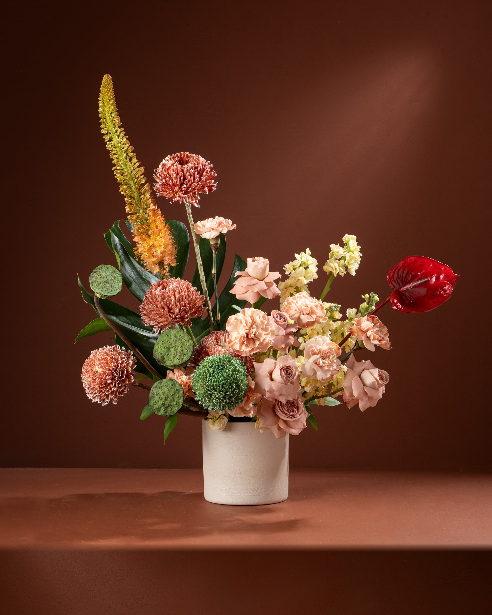 Floral arrangement in a white vase on a brown surface with a brown background