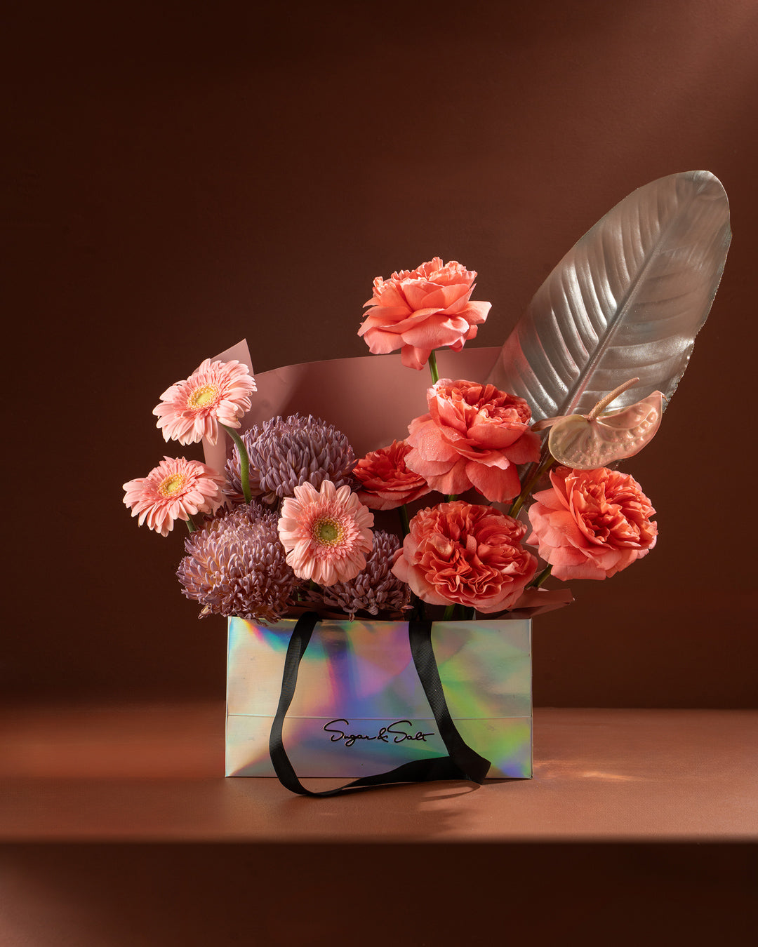 Bouquet of flowers in a colorful gift bag on a brown background