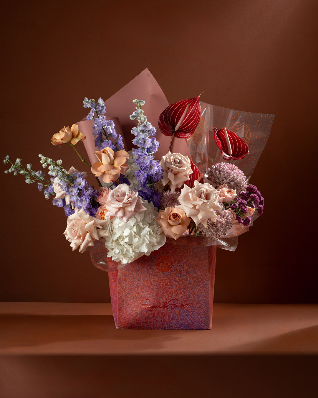Bouquet of flowers in a pink box against a brown background