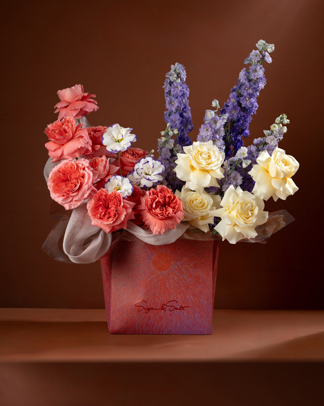 Colorful flower arrangement in a red box on a brown background