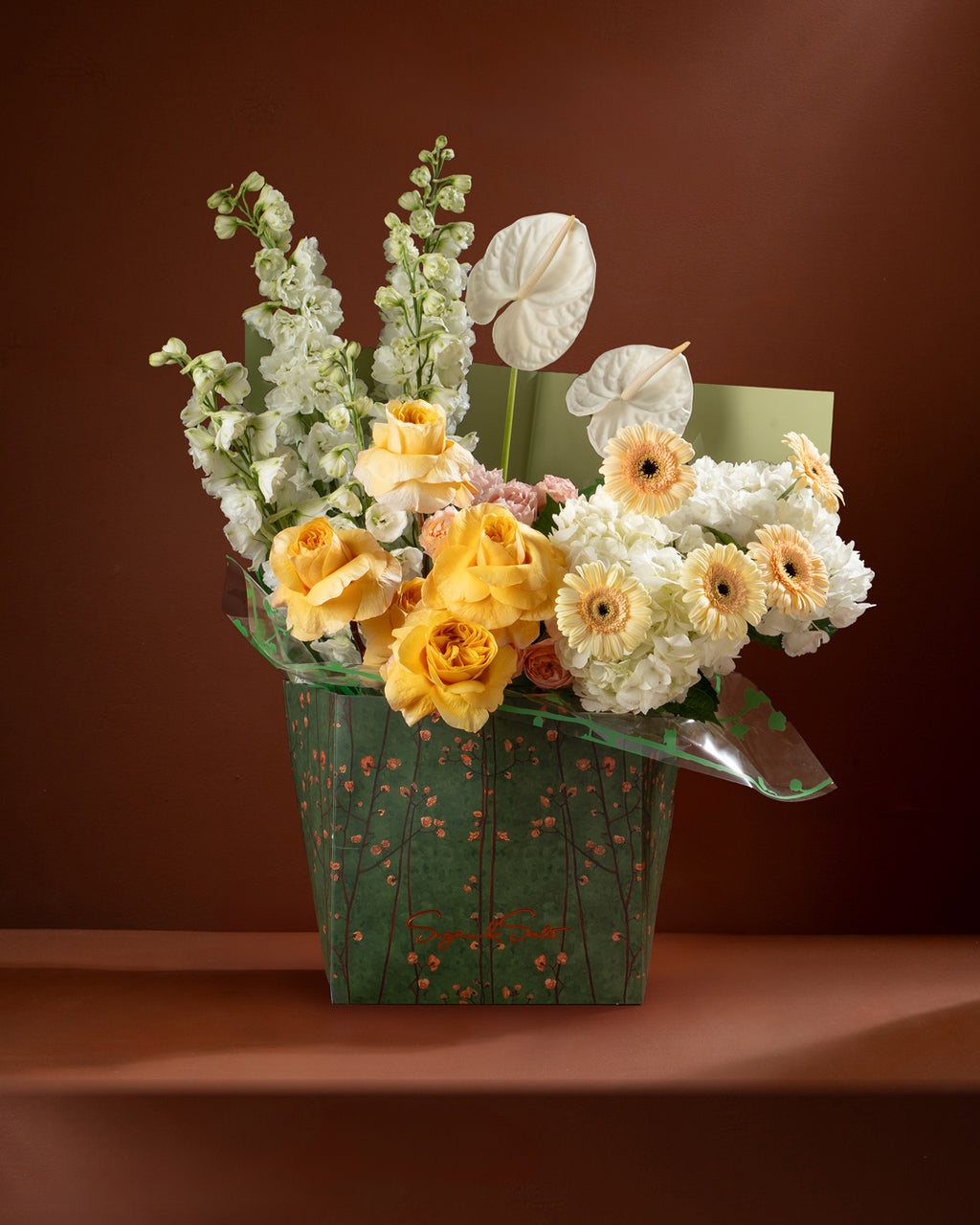 Bouquet of flowers in a green paper basket on a brown background