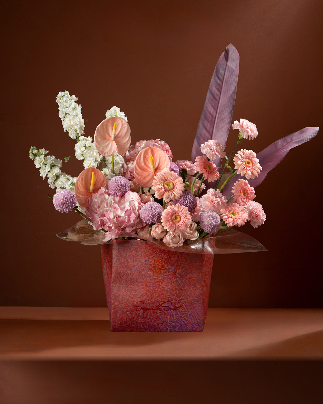 Bouquet of flowers in a red box with a brown background